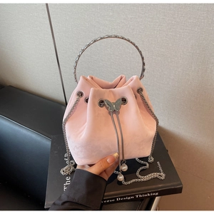 Detail of pink velvet bucket bag featuring metal butterfly and pearl charms decoration