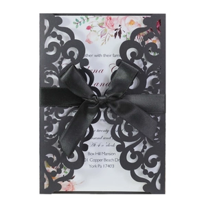Détail de l'invitation de mariage découpée au laser avec motifs noirs et ruban de satin