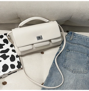 Detail of off-white rectangle handbag with silver turn-lock and adjustable shoulder strap