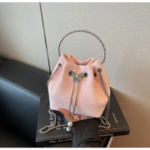 Detail of pink suede bucket bag featuring silver handle and pearl butterfly charm