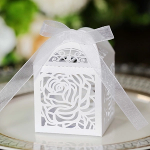 Macro view of white laser-cut rose candy box with chiffon ribbon on a ceramic plate
