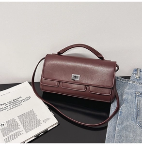Detail of a dark mahogany leather handbag with silver twist lock and fashion magazine