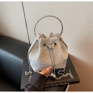Detail of silver bucket bag with metal handle, butterfly pearl clasp and chain strap