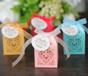 Detail of pink laser-cut wedding favor box with heart pattern and thank you tag