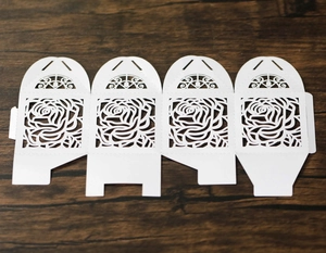 Flat lay of white laser-cut paper gift box template with intricate rose patterns