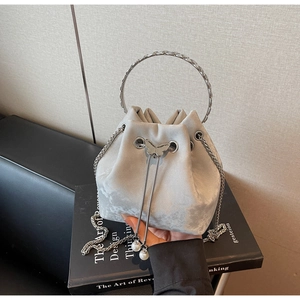 Detail of grey suede bucket bag with silver butterfly clasp and pearl drawstring beads