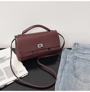 Detail of burgundy leather handbag with silver twist lock and top handle in lifestyle setting