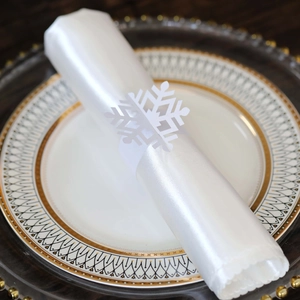 Close-up of laser-cut white snowflake paper napkin ring on a festive table setting