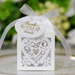 Close-up of laser-cut heart candy box with white organza ribbon and golden thank you tag