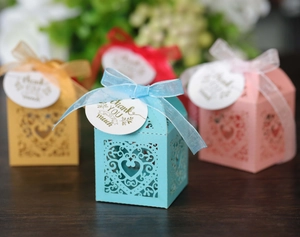 Detail of laser-cut heart favor boxes in multiple colors with silk bows and thank you tags