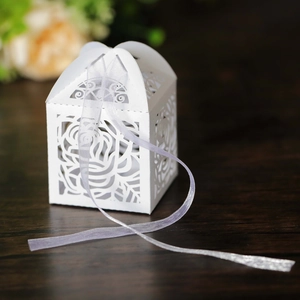 Detail of laser cut white rose gift box with elegant ribbon on wooden table