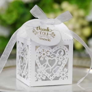 Macro detail of laser-cut heart favor box with white ribbon and thank you tag