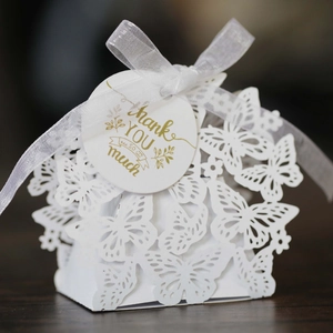 Close-up of white laser-cut butterfly gift box with silk ribbon and Thank You tag
