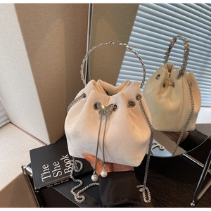 Detail of beige suede bucket bag with silver butterfly charm and pearl drawstrings