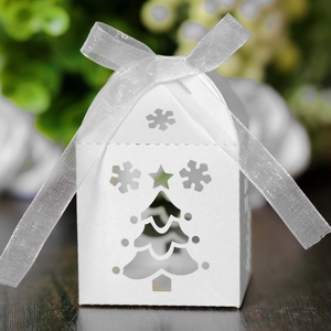 Detail of white laser-cut Christmas candy box with snowflake tree and organza ribbon