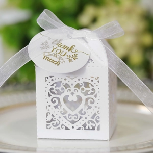 Macro detail of white laser-cut hollow heart candy box with ribbon and gold foil tag