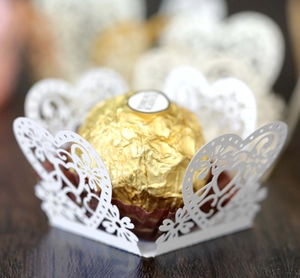 Macro view of white laser-cut paper heart lace chocolate wrapper for wedding party decor