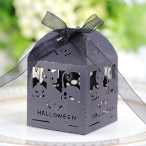 Detail of black laser-cut Halloween candy box with pumpkin and cat motifs on a plate