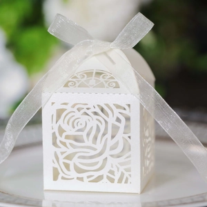 Detailed laser-cut rose patterns on white wedding favor box with a silk ribbon bow
