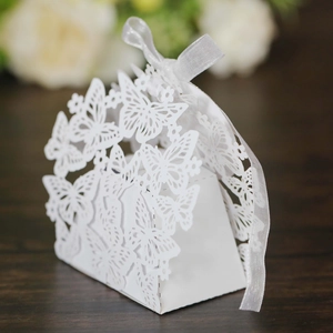 Detail view of laser-cut butterfly wedding favor box in white paper with silk ribbon
