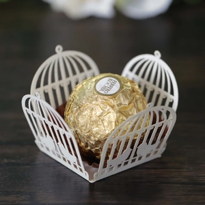 Macro view of laser-cut birdcage candy box with intricate floral and bird patterns