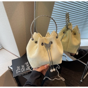 Detail of yellow drawstring bucket bag with silver butterfly charm and pearl accents