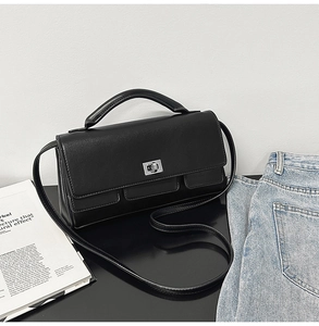 Detail of black lychee texture handbag with silver metal turn-lock and leather handle