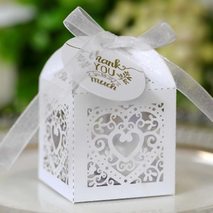 Detail of white laser-cut gift box with hollow heart pattern and silk ribbon bow