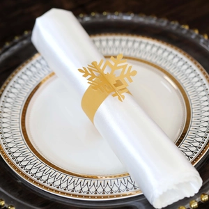 Close-up of golden hollow snowflake napkin ring on white silk for Christmas table decor