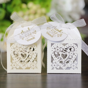 Detail of laser-cut heart favor boxes with organza ribbons and gold thank you tags