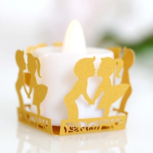 Macro view of gold hollow-out paper sleeve with boy, girl and rose patterns for LED candle