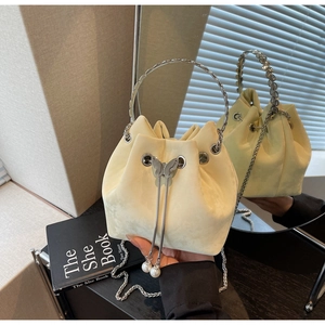Detail of beige bucket bag with silver butterfly clasp, pearl charms, and metal handle