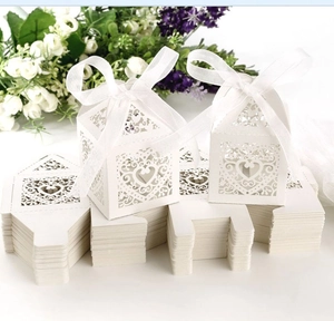 Detail of white laser-cut wedding favor box with heart pattern and satin ribbon