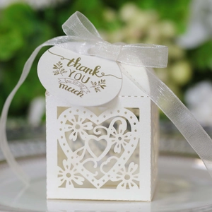 Detail of white hollow favor box with heart laser cut patterns and thank you tag
