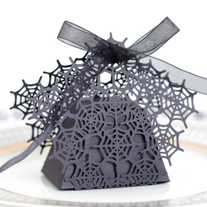 Detailed laser-cut spider web pattern on a black Halloween favor box with a silk ribbon