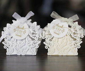 Detail of laser-cut butterfly favor boxes with thank you tags and ribbon bows