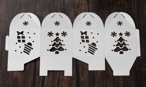 Flat lay of laser-cut white Christmas tree gift box template with snowflake patterns