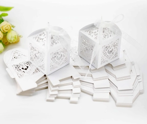 Close-up of white laser-cut hollow heart favor box with elegant white ribbon and floral patterns