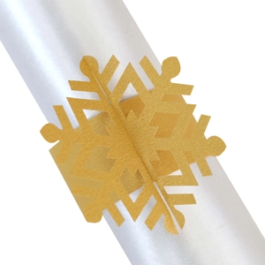 Macro shot of gold snowflake paper napkin ring with elegant laser-cut hollow pattern