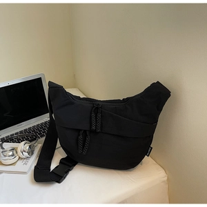 Detailed close-up of a black canvas crossbody bag with durable zippers and a woven puller