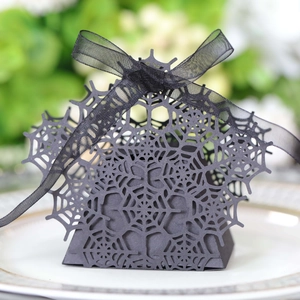 Detail of laser-cut spider web pattern on matte black Halloween candy box with ribbon