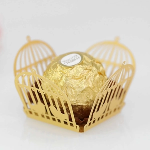 Close-up of golden laser-cut paper birdcage favor box with intricate hollow patterns