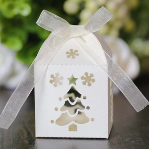 Macro shot of laser-cut white Christmas tree gift box with elegant white ribbon bow