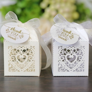 Detail of laser-cut heart candy boxes with ivory ribbons and gold thank you tags
