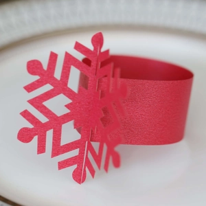 Macro shot of red snowflake napkin ring with intricate cutout design on white plate