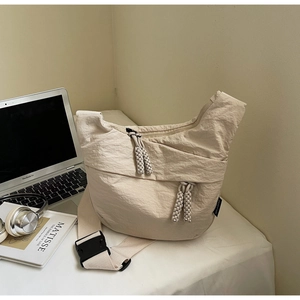 Detailed shot of beige nylon crossbody bag texture with adjustable wide strap and zipper