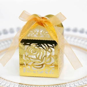 Detailed view of golden laser-cut wedding favor box with rose pattern and ribbon