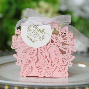 Close-up of pink laser-cut butterfly favor box with silver ribbon and thank you card