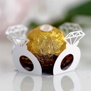 Close-up of laser-cut white paper candy holder in wedding ring shape with hollow diamond