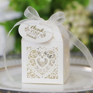 Close-up of laser-cut white heart gift box with ribbon and gold thank you tag
